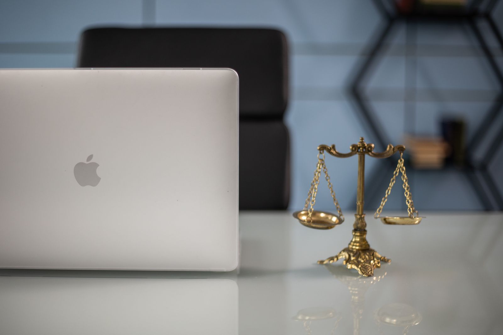 Laptop beside brass scales of justice on a desk